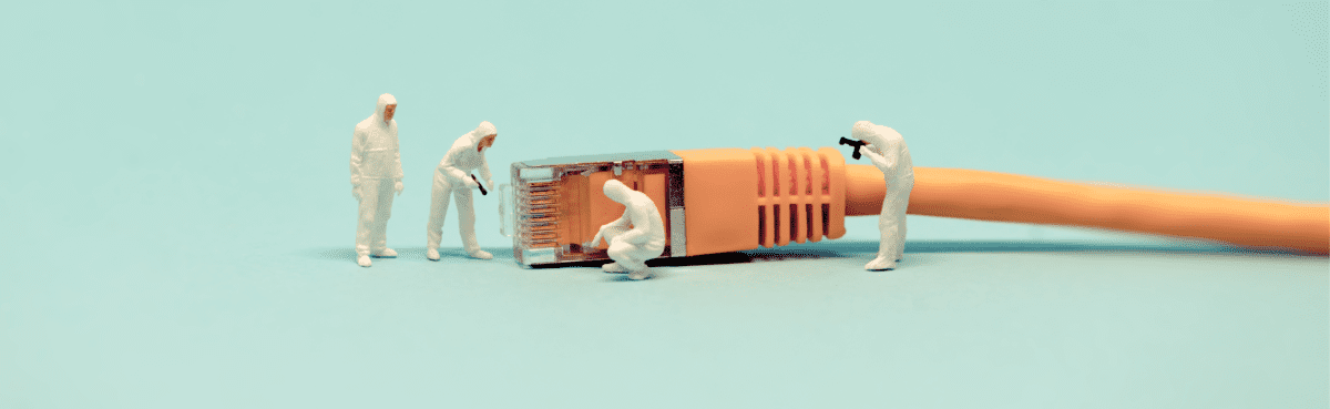 tiny toy workers examining ethernet cord 