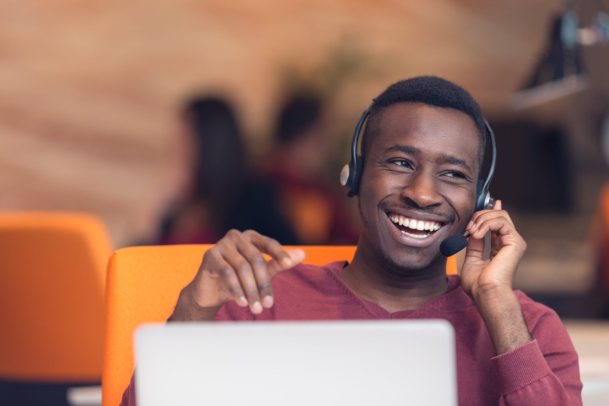 man working on computer with headset smiling