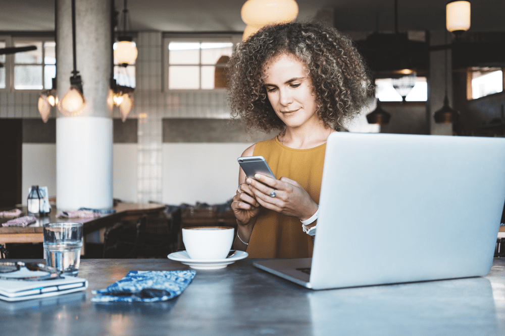 woman at desk checking cell phone