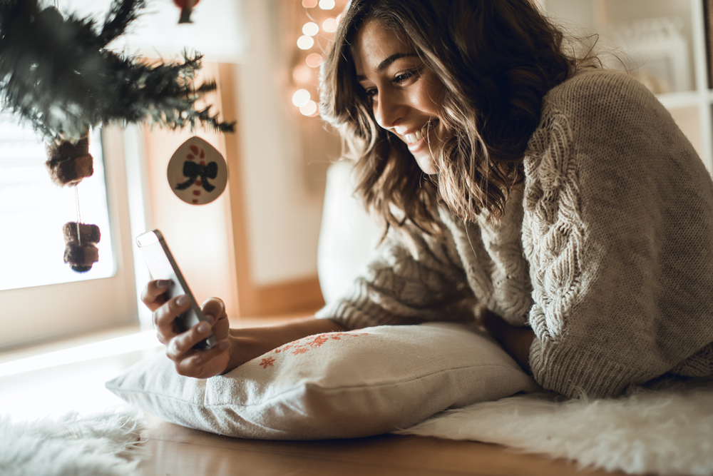 woman texting by christmas tree