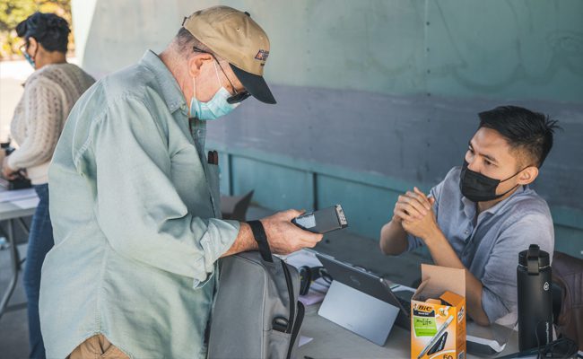 man giving electronics to another person